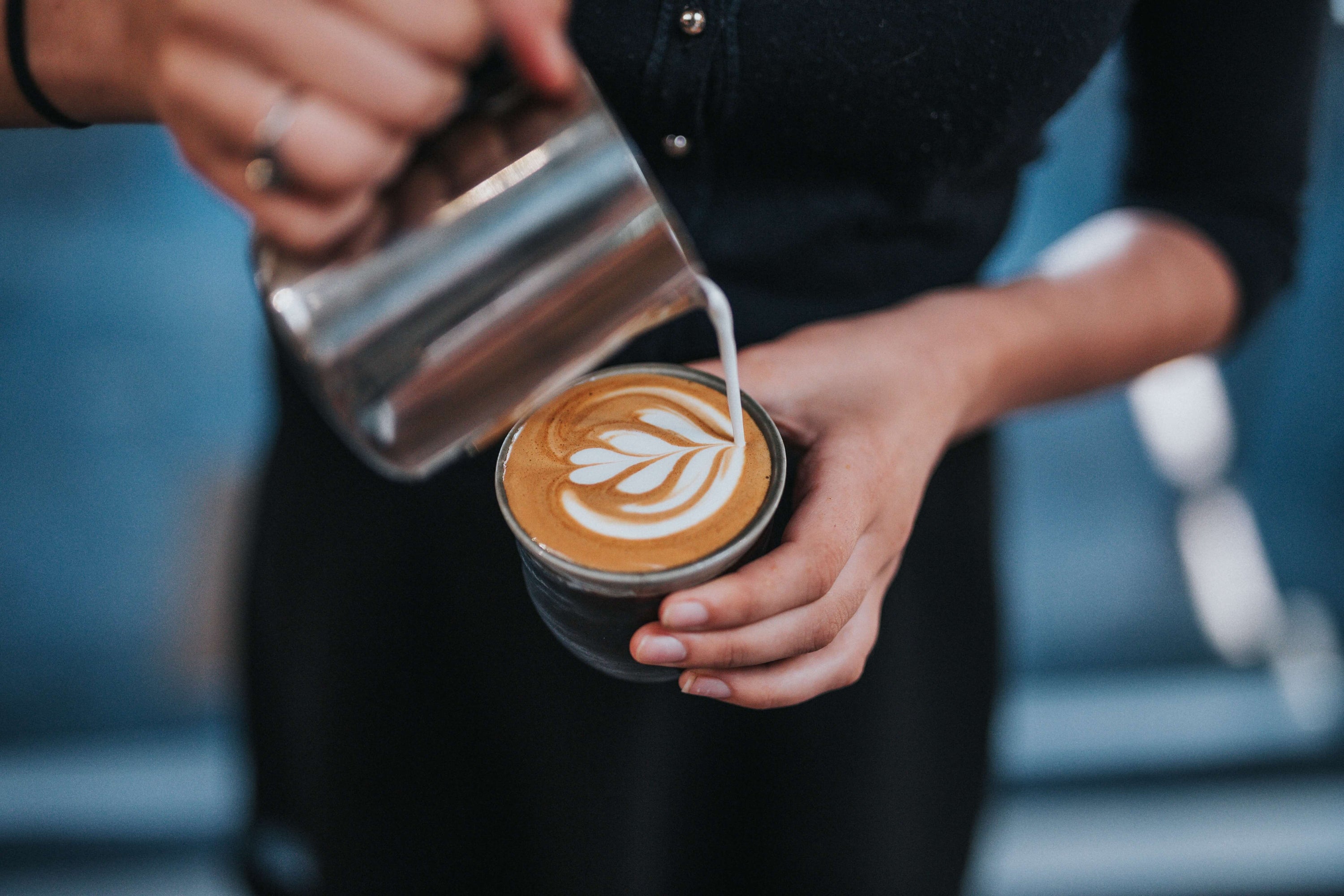 man pouring milk into coffee cup