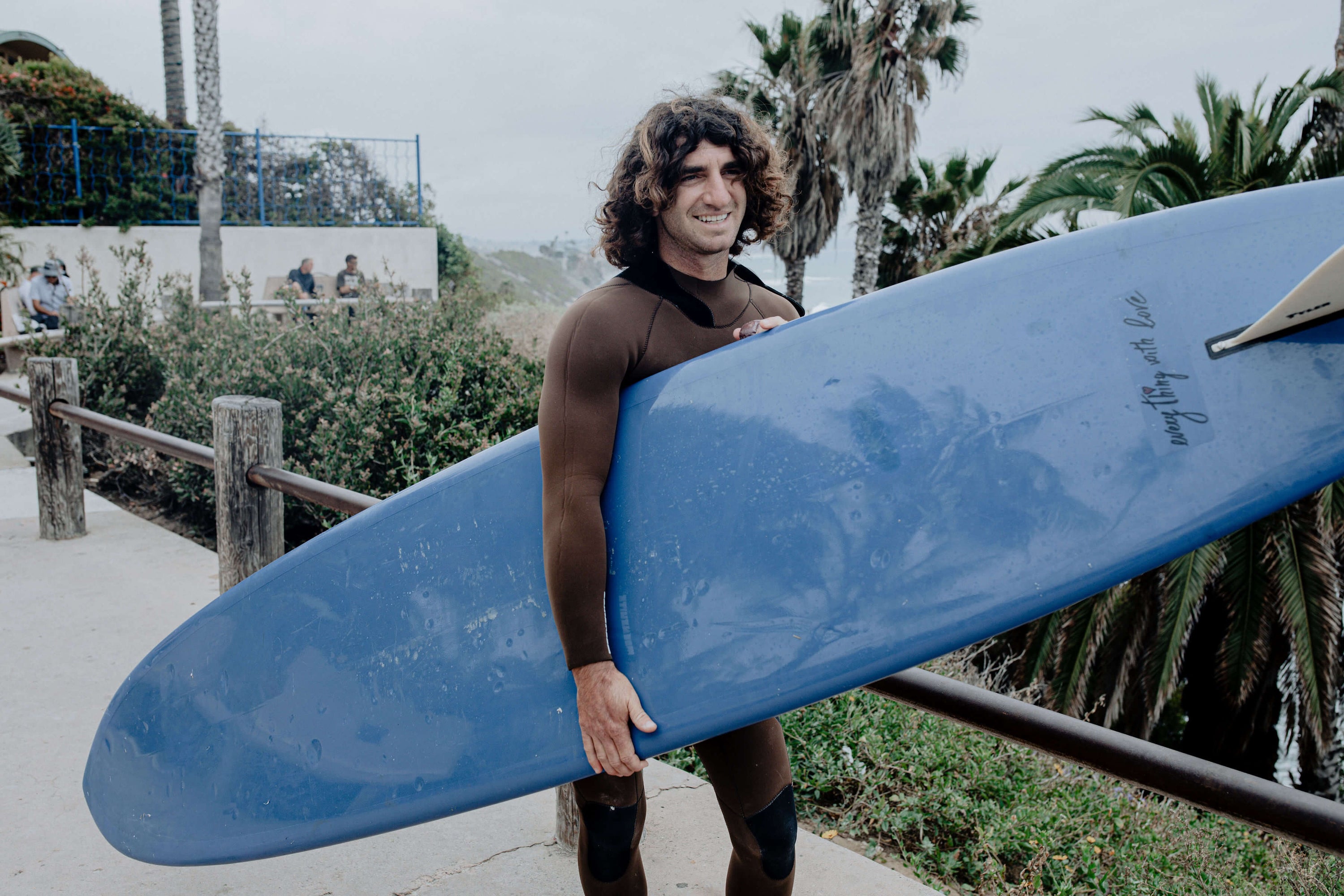 Man carrying blue surfboard in california